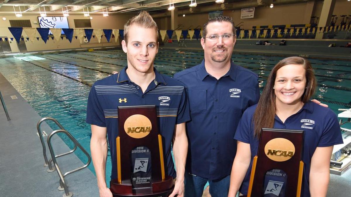 Queens swim coach Jeff Dugdale flanked by Royals swimmers Dion Dreesens, left, and Caroline Arakelian hold the men’s and women’s championship trophies from the 2016 NCAA Division II National Championships, held March 9-12 in Indianapolis, Ind. Queens repeated as men’s and women’s champions, and Dreesens was named the men’s most outstanding swimmer.