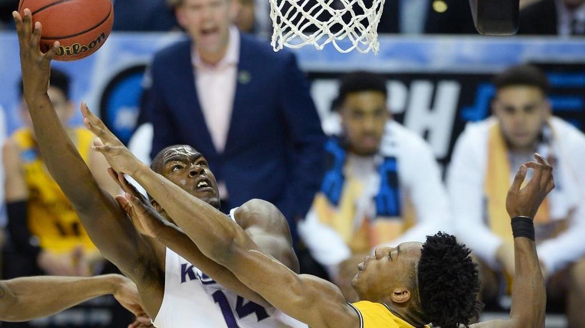 Kansas State forward Makol Mawien, left, fights to get a shot off in the lane as UMBC Retrievers forward Daniel Akin, right, applies defensive pressure during Sunday’s second-round NCAA tournament game at the Spectrum Center. Kansas State defeated UMBC 50-43.