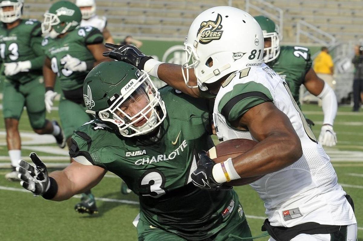 Charlotte 49ers redshirt senior wide receiver Trent Bostick, right, stiff-arms redshirt sophomore linebacker Jeff Gemmell during Saturday’s spring football game at Richardson Stadium.
