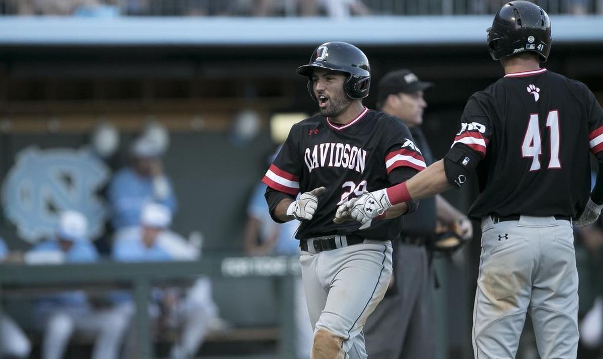 Davidson’s Jake Sidwell is greeted at home plate by Will Robertson as he scores to give the Wildcats an 8-0 lead over the Tar Heels on Friday. Sidwell scored on a single by Cam Johnson.