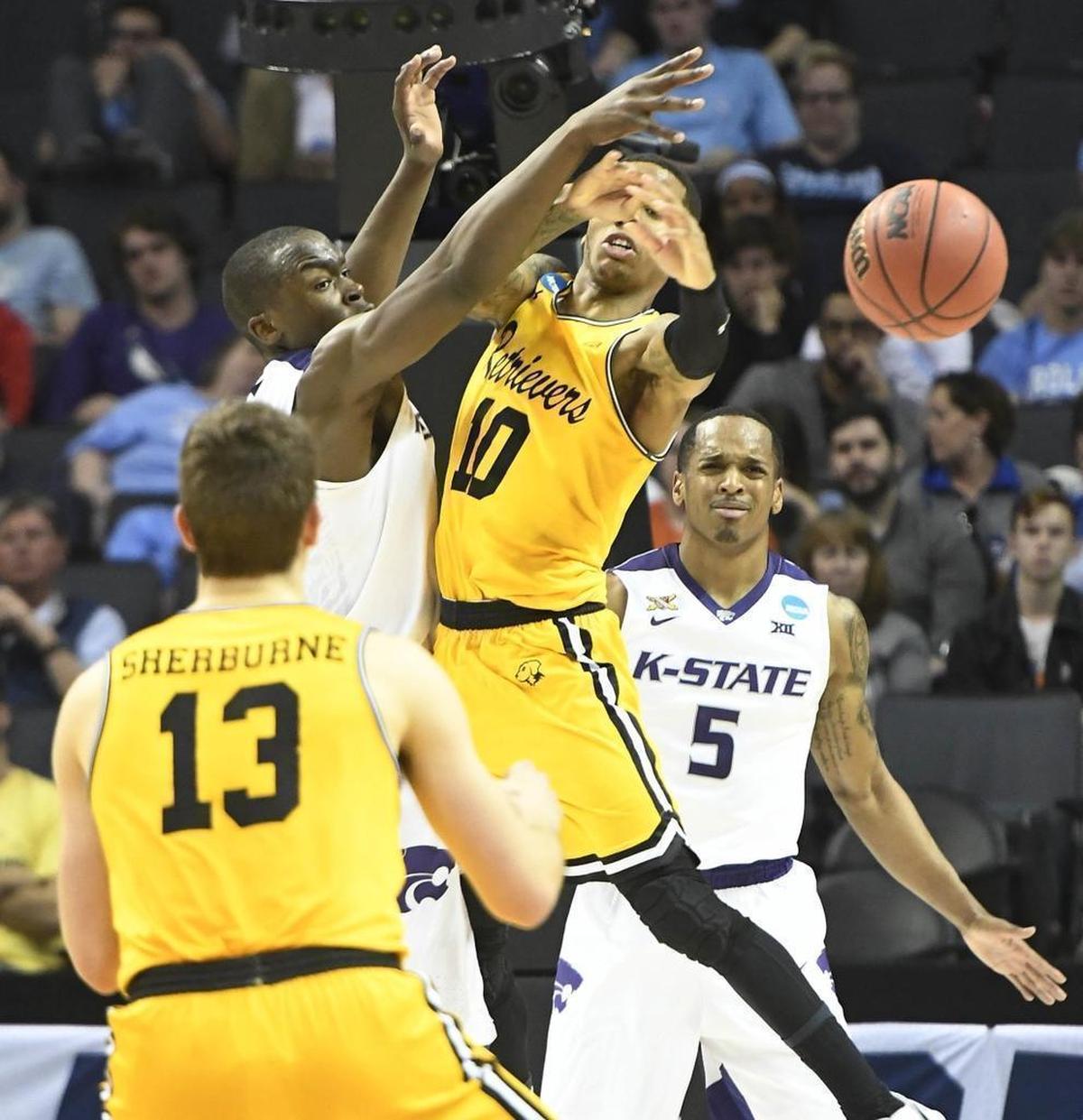 UMBC Retrievers guard Jairus Lyles (10) passes to teammate Joe Sherburne (13) as Kansas State Wildcats forward Makol Mawien (14) defends during Sunday’s second-round NCAA tournament game at the Spectrum Center.