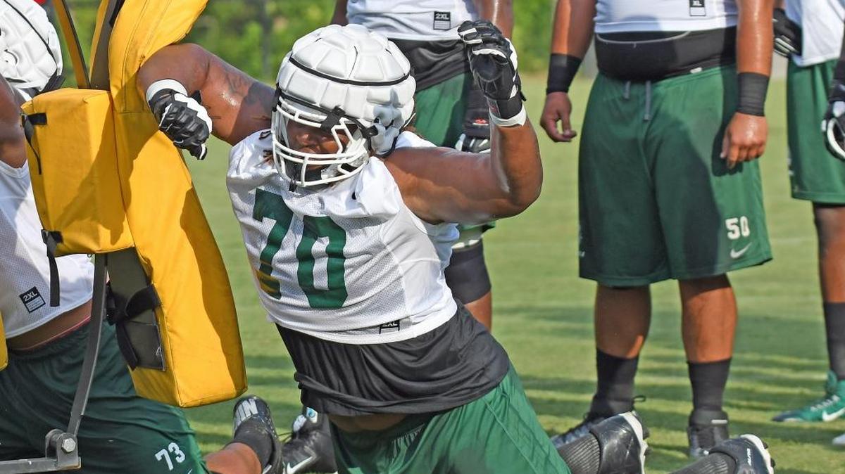 Charlotte offensive lineman Casey Perry (70) hits the blocking sled with his forearm during a drill at the opening day of the 49ers’ summer practices Wednesday. Charlotte opens its season Sept. 1 at Louisville.