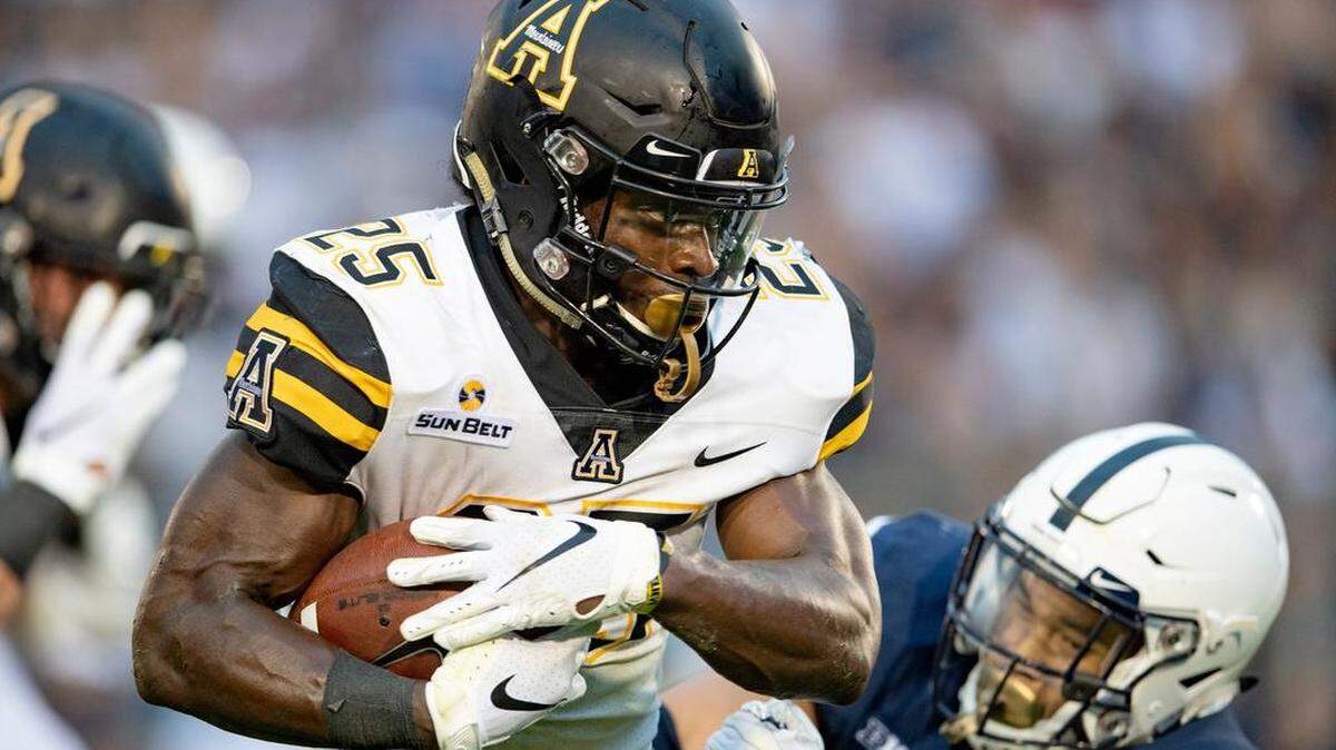 Appalachian State running back Jalin Moore, left, is pictured on Saturday bowling past Penn State linebacker Koa Farmer on a 16-yard touchdown run in the Mountaineers’ 45-38 overtime loss to the Nittany Lions. Moore, who is from Shelby, and his teammates will visit the Charlotte 49ers on Saturday.