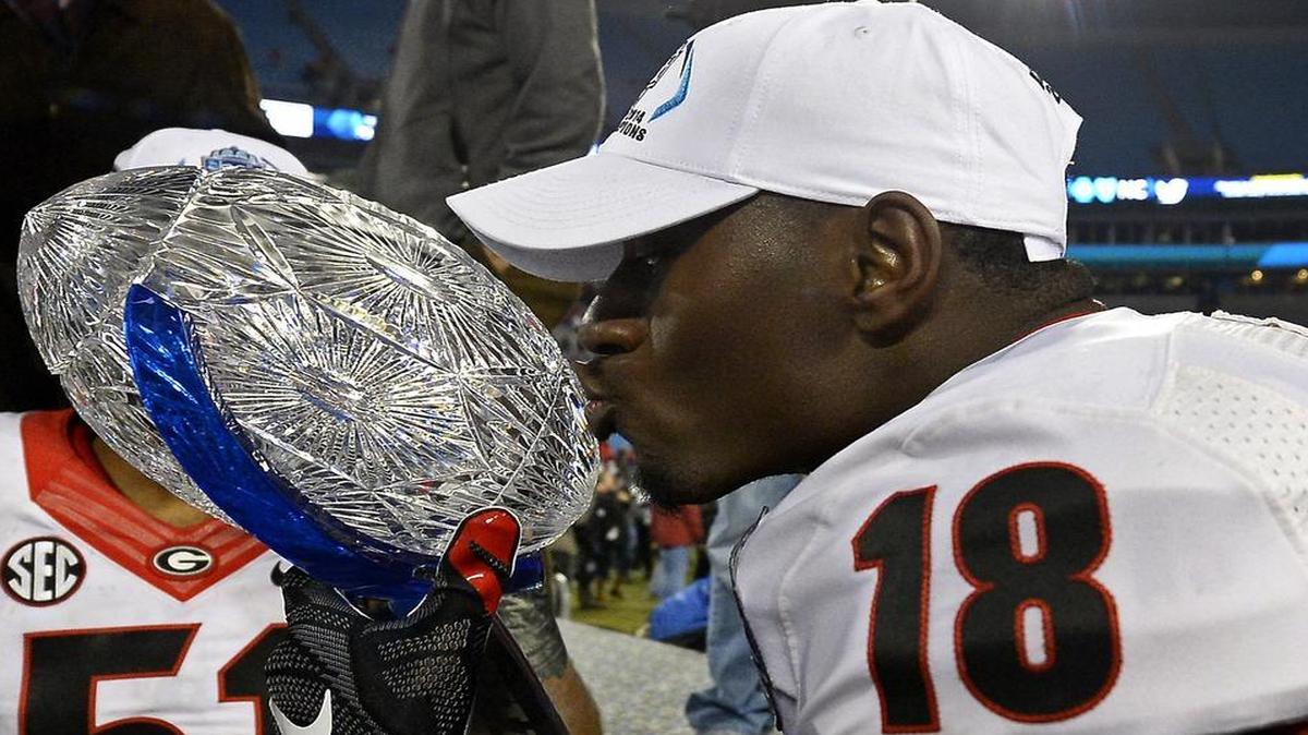 
Georgia Bulldogs split end Jonathon Rumph (18) kisses the championship trophy following the team's victory over the Louisville Cardinals in the Belk Bowl at Bank of America Stadium in Charlotte, NC on Dec. 30, 2014. The Bulldogs defeated the Cardinals 37-14.
