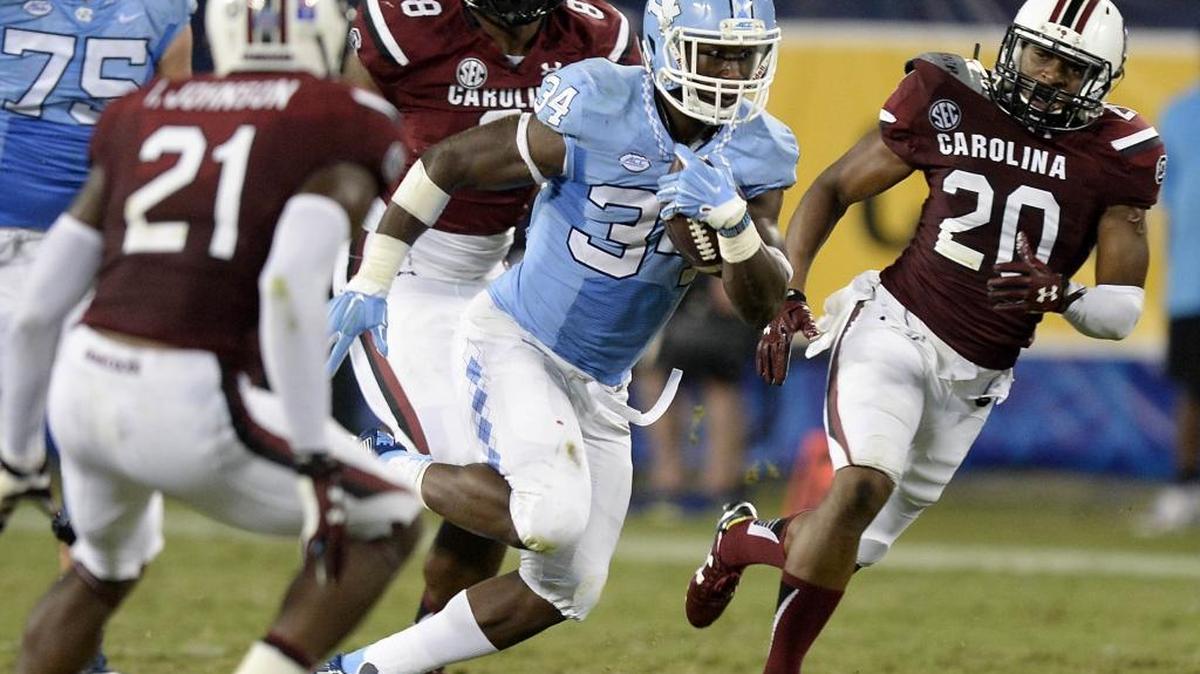 
North Carolina Tar Heels running back Elijah Hood (34) accelerates past South Carolina Gamecocks' T.J. Gurley (20) and Marquavius Lewis (8) during the second half in the Belk College Kickoff season opener at Bank of America Stadium on Thursday. South Carolina won, 17-13
