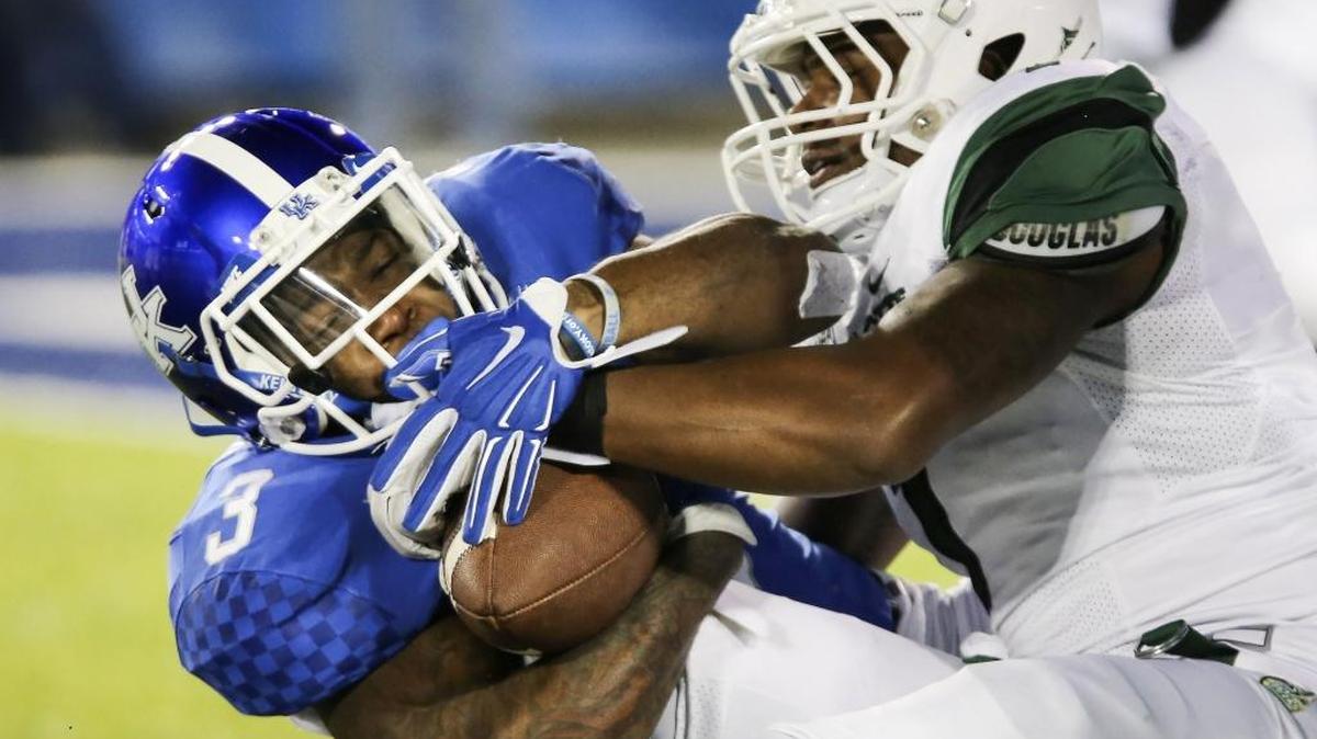 Kentucky running back Jojo Kemp keeps a grip on the ball as he is tackled by Charlotte linebacker Jalen Holt during the first half of an NCAA college football game Saturday in Lexington, Ky.