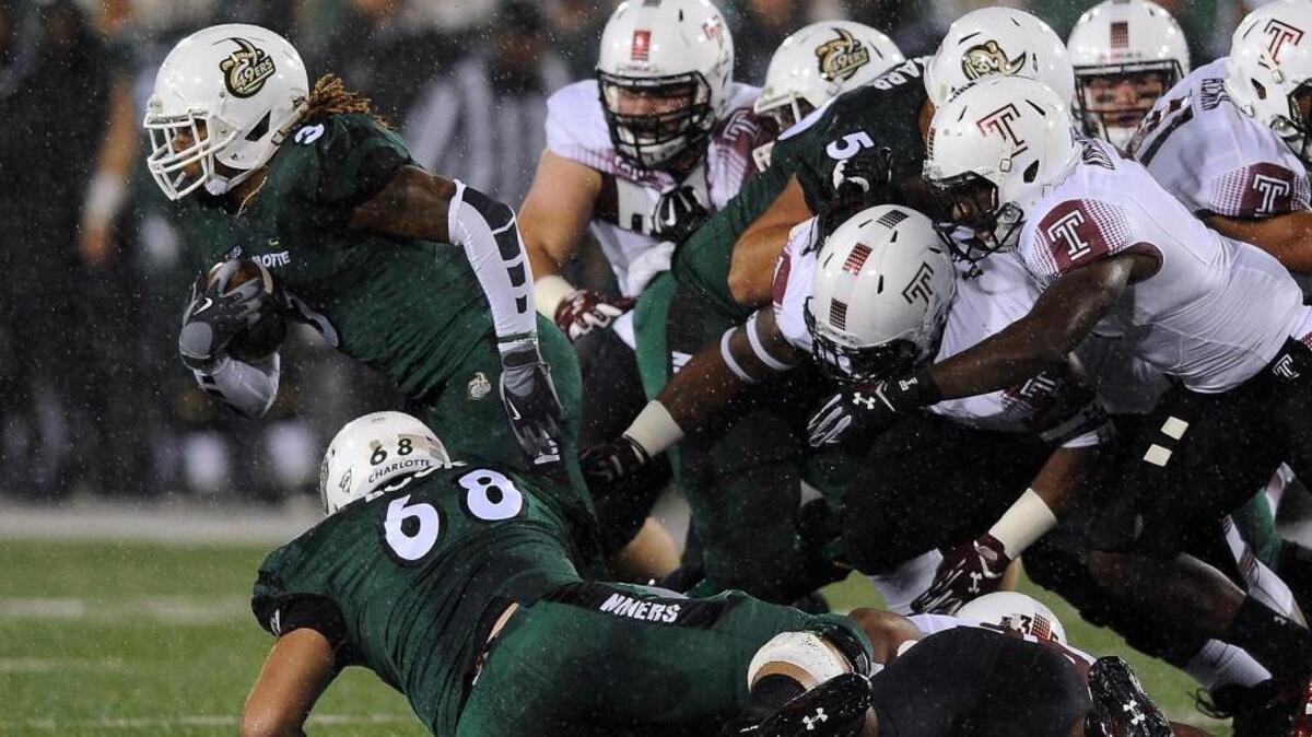
Charlotte 49ers running back Kalif Phillips, left, breaks free of the Temple Owls defense on a run during first quarter action at Jerry Richardson Stadium on Friday, October 2, 2015. 
