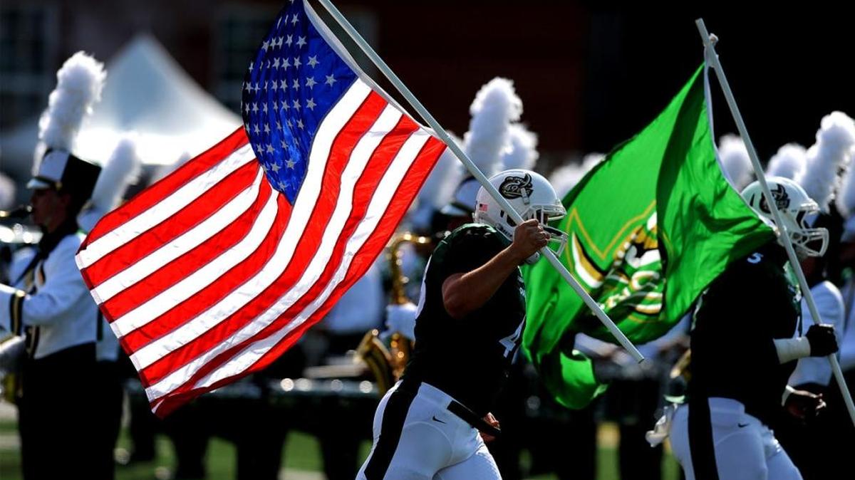 The afternoon light highlights the American flag as it is carried onto the field prior to the Charlotte 49ers - Southern Miss game at Jerry Richardson Stadium.