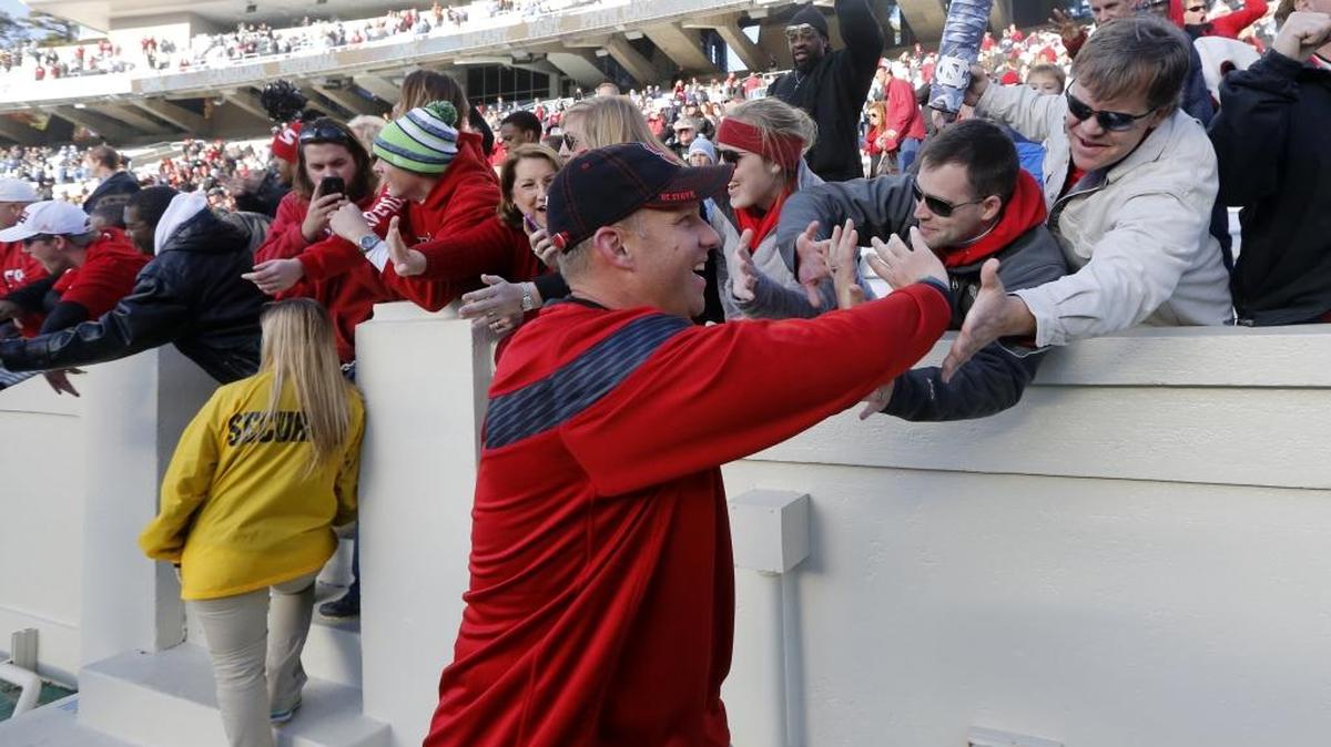 
N.C. State head coach Dave Doeren high-fives fans after N.C. State's 35-7 victory over North Carolina at Kenan Stadium in Chapel Hill, Nov. 29, 2014.
