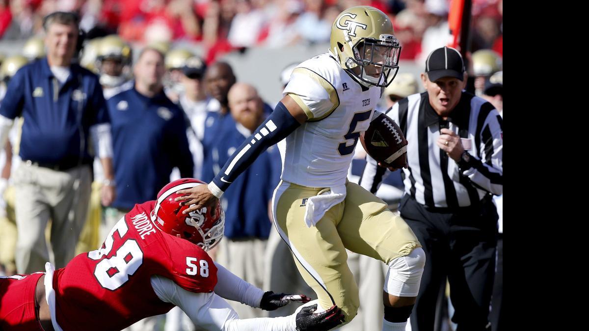 
Georgia Tech quarterback Justin Thomas (5) tries to escape from N.C. State linebacker Airius Moore (58)  at Carter-Finley Stadium in Raleigh, Nov. 8, 2014.
