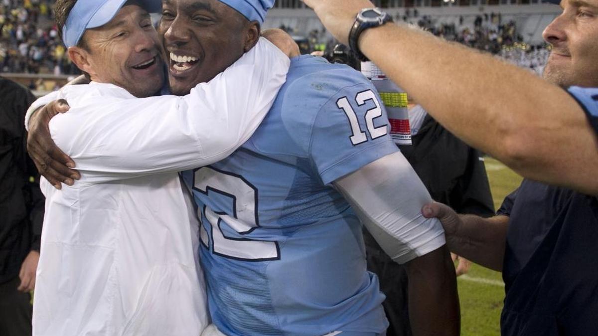 
North Carolina coach Larry Fedora and offensive line coach Chris Kapilovic embrace North Carolina quarterback Marquise Williams (12) as they celebrates the Tar Heels 41-38 victory over Georgia Tech with fans on Saturday, October 3, 2015 in Atlanta, Georgia. 
