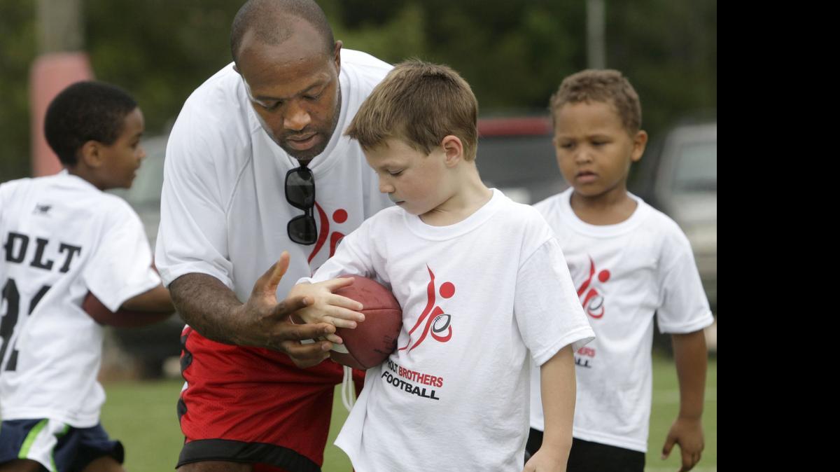 
Seven-time NFL Pro Bowl wide-receiver Torry Holt, shows Chandler Fleming, 6, how to hold on to the ball during a youth football camp at the WRAL Soccer Center in North Raleigh on Friday, July 13, 2012. Modeled on the one they hold in their hometown of Gibsonville, it was Torry and his brother Terrence Holt's first time holding camp in Raleigh.

