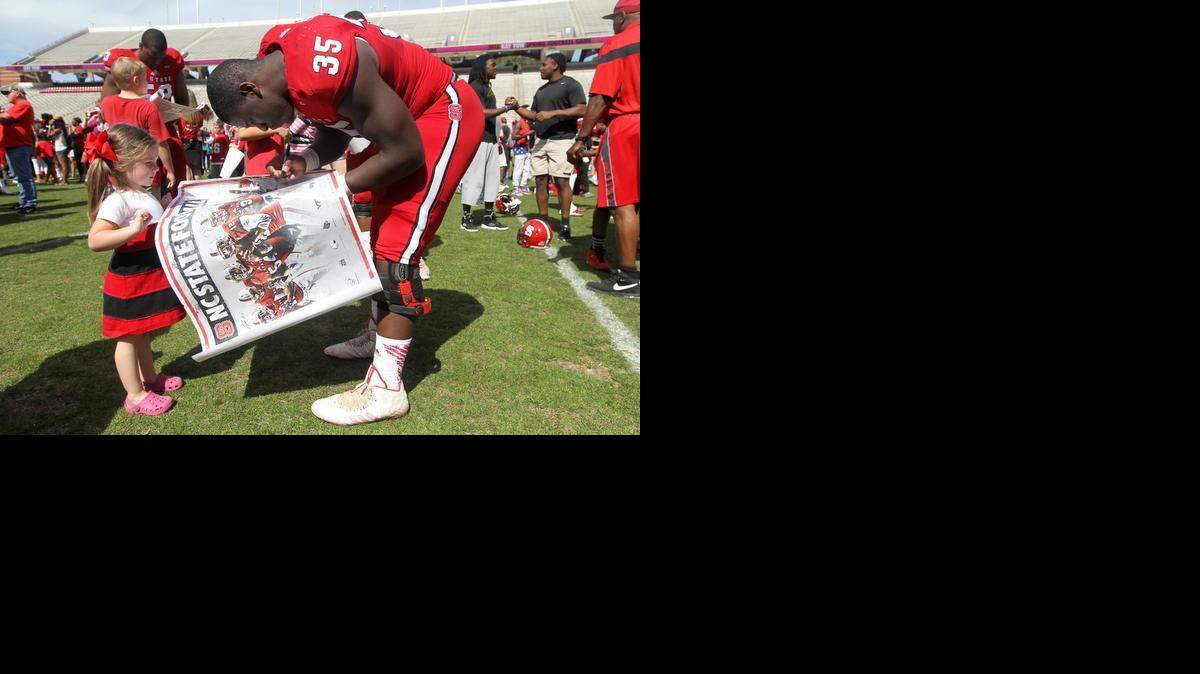 
N.C. State defensive end Kentavius Street signs an autograph for Jillian Jarrell, 3, of Salisbury after the 2015 Kay Yow Spring Game at Carter-Finley Stadium in Raleigh.
