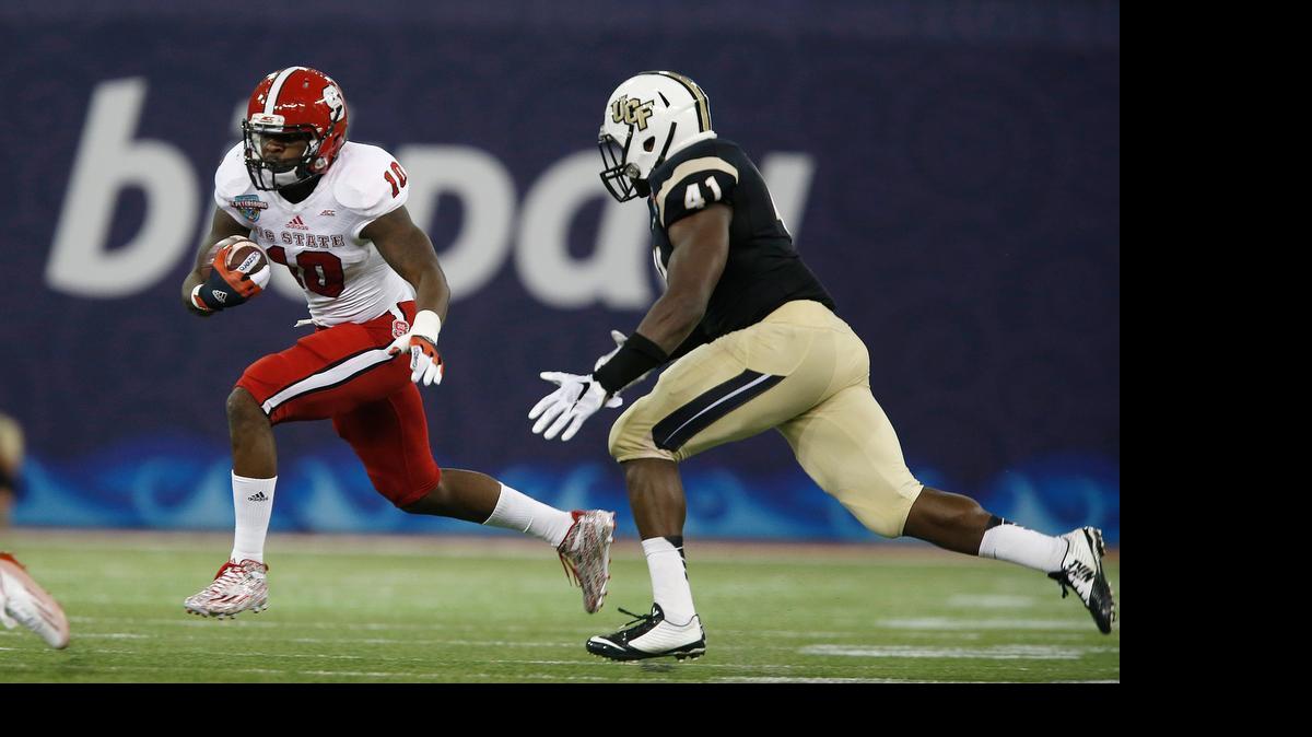 
N.C. State running back Shadrach Thornton looks for running room as UCF linebacker Terrance Plummer closes in during the Wolfpack’s Bitcoin St. Petersburg Bowl win on Dec. 26, 2014. 
