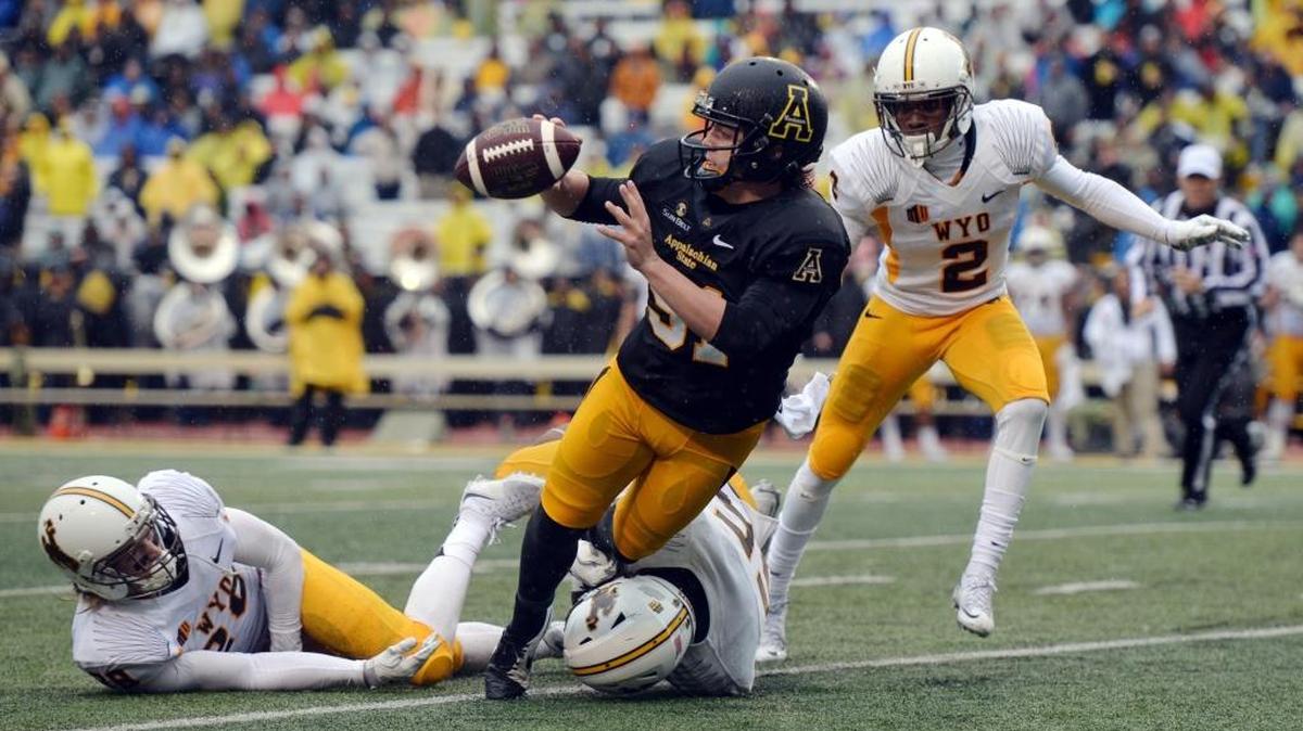 Appalachian State holder Caleb Fuller (51) pitches out to kicker Zach Matics on a fake field goal attempt despite pressure from Wyoming defenders Andrew Windgard , left, Troy Boyland, bottom center, and Robert Priester in the second quarter of an NCAA college football game at Kidd Brewer Stadium in Boone, Saturday.