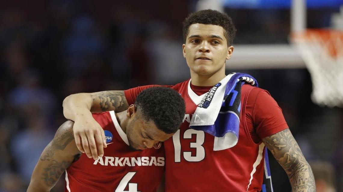 Arkansas' Daryl Macon (4) is consoled by Dustin Thomas (13) after Sunday’s second-round NCAA tournament loss. After blowing a 17-point lead, No. 1 seed North Carolina came from behind in the second half to win 72-65.
