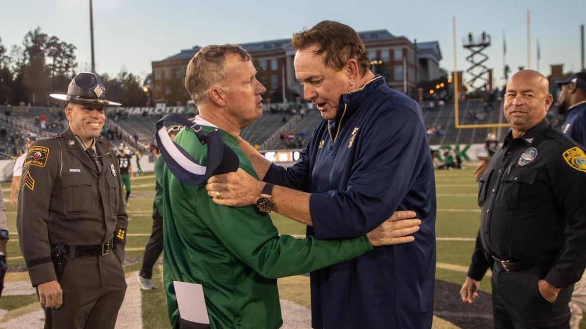 Charlotte 49ers coach Brad Lambert, left, and Florida International coach Butch Davis meet at midfield after Saturday’s Conference USA football game at Richardson Stadium. FIU won 42-35.