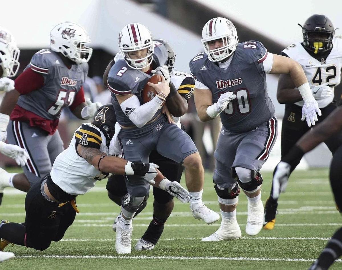 Massachusetts’s Ross Comis (2) carries the ball upfield as Appalachian State’s Caleb Fuller, left, Myquon Stout attempt to bring him down during the first quarter of Saturday’s game.