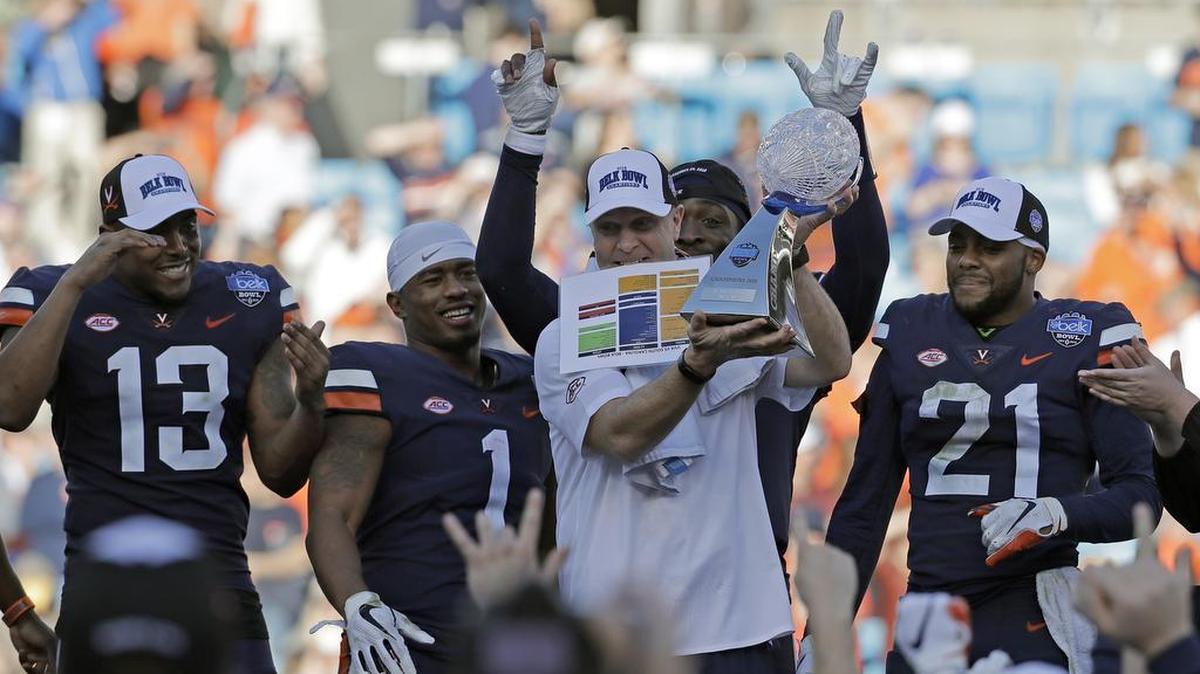 Virginia football coach Bronco Mendenhall and his players celebrate their 28-0 shutout win over South Carolina in the Belk Bowl on Saturday at Bank of America Stadium.