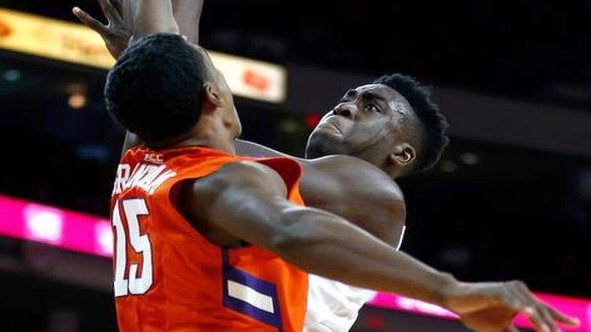 
N.C. State's Abdul-Malik Abu (0) shoots while Clemson's Donte Grantham (15) defends during the second half of Clemson's 68-57 victory over N.C. State at PNC Arena in Raleigh, Jan. 28, 2015.
