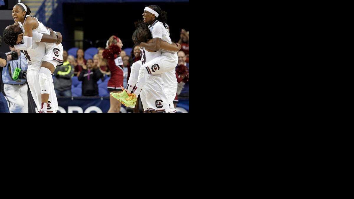 
South Carolina's Tiffany Mitchell, top left, is hugged by Aleighsa Welch while Tina Roy, bottom right, hugs Khadijah Sessions as they celebrate after a women's college basketball regional semifinal game against North Carolina in the NCAA Tournament in Greensboro, N.C., Friday, March 27, 2015. South Carolina won 67-65.
