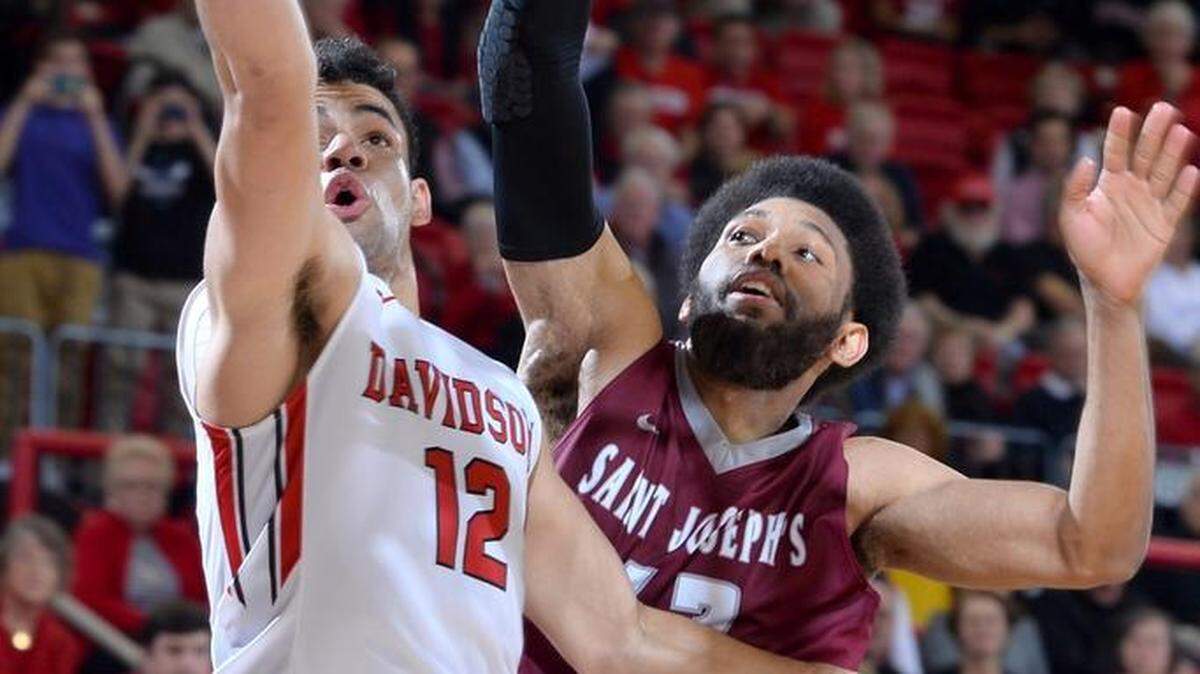 Davidson’s Jack Gibbs (12) drives and gets fouled by Papa Ndao (12) of Saint Joseph's in second half A-10 men's basketball action at the John M. Belk Arena on Saturday. Gibbs would finish with a game-high 35 points as Davidson won 99-93.