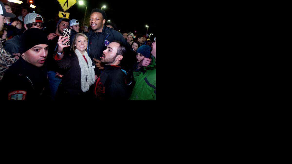 
Celebrating their victory against North Carolina at the Smith Center in Chapel Hill, thousands of cheering N.C. State students surrounded the school’s Bell Tower, flooded into Hillsborough Street in Raleigh on Tuesday. Posing for a photo with fans was the Wolfpack’s BeeJay Anya, top right.
