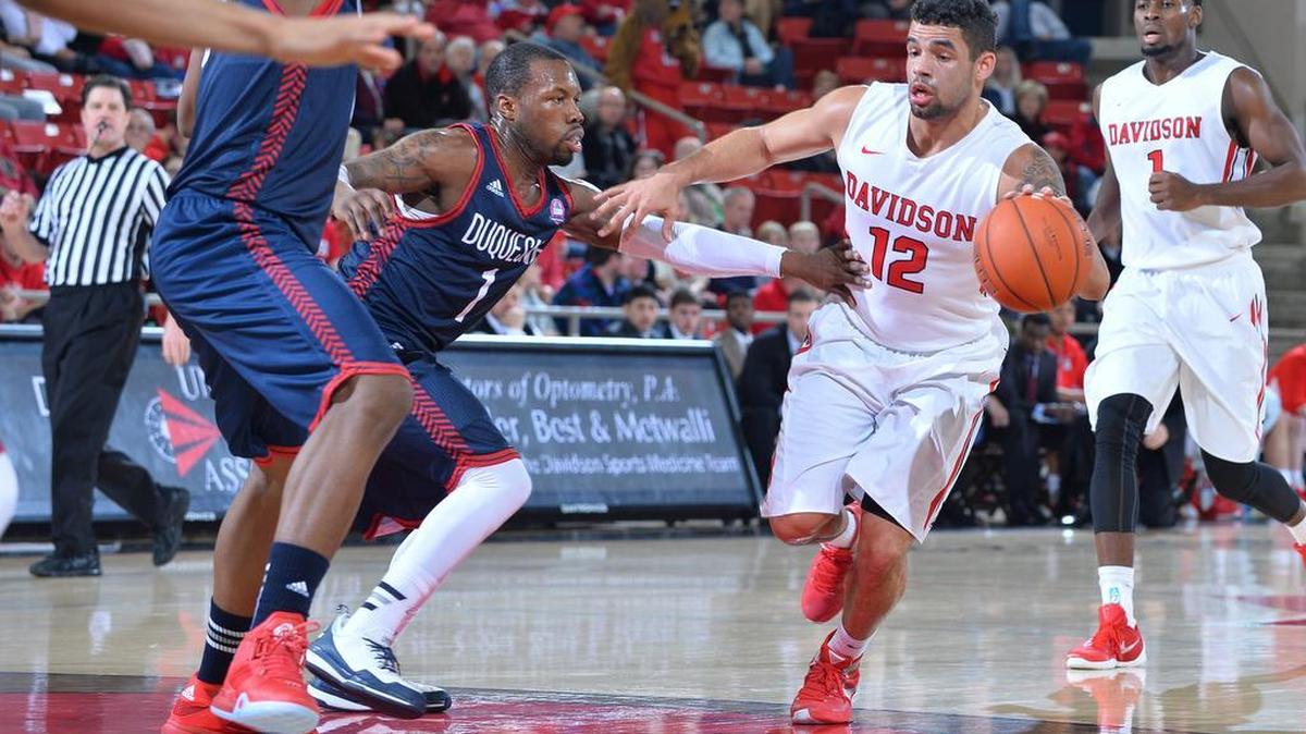 Jack Gibbs (12) of Davidson drives to the basket against Derrick Colter (1) of Duquense in first half action at John M. Belk Arena on Wednesday, January 06, 2016 in Davidson, North Carolina. Davidson leads at half 38-36.