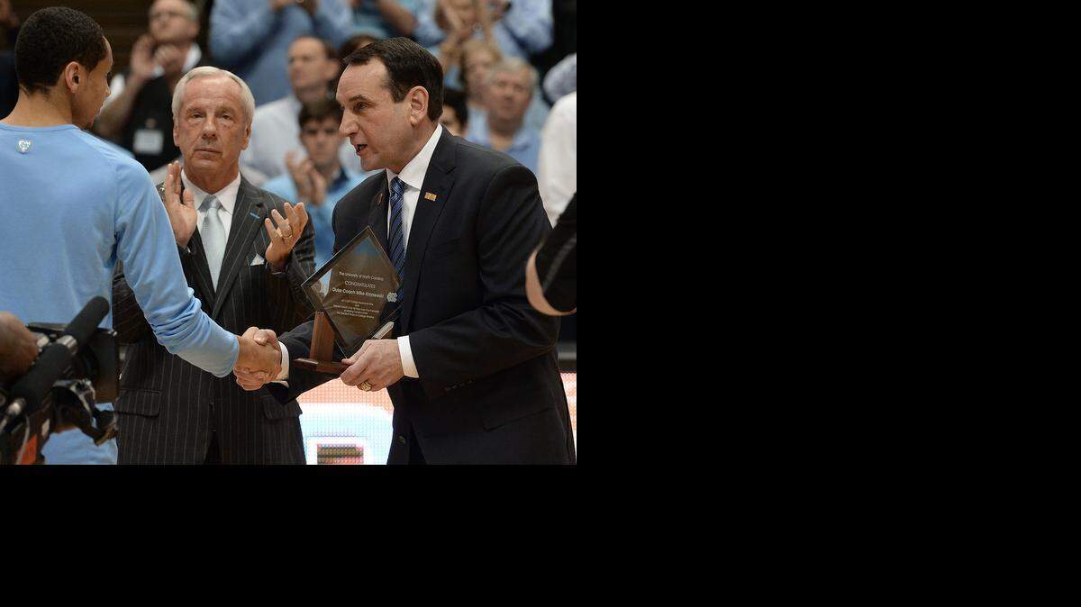 
Duke head coach Mike Krzyzewski receives a commemorative trophy from UNC guard Marcus Paige (5) as UNC head coach Roy Williams looks on for his 1000 career wins before the UNC game. Duke defeated UNC 84-77 at the Dean Smith Center in Chapel Hill, Saturday, March 7, 2015 in the final game of the regular season.
