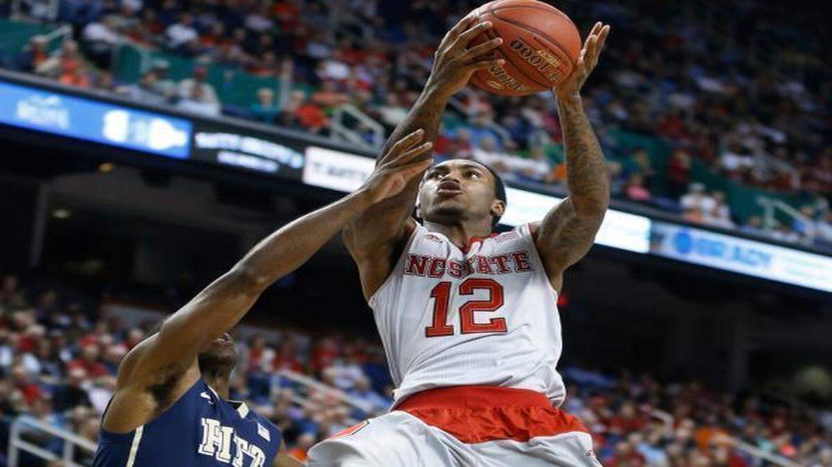 
N.C. State's Cat Barber (12) drives to the basket past Pitt's Josh Newkirk (13) during the first half of N.C. State's game against Pittsburgh.

