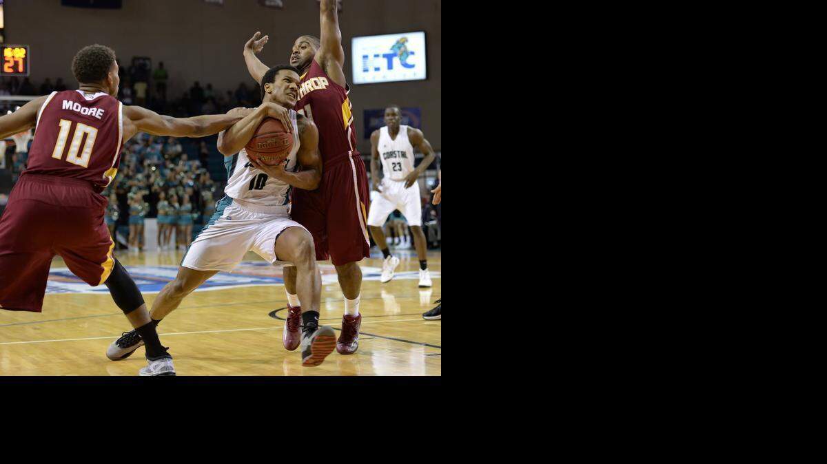 
Coastal Carolina’s Shivaughn Wiggins, center, drives to the basket while pressured by Winthrop’s Keon Moore, left, and Andre Smith during the first half of the Big South Conference Championship NCAA college basketball game Sunday in Conway, S.C. 
