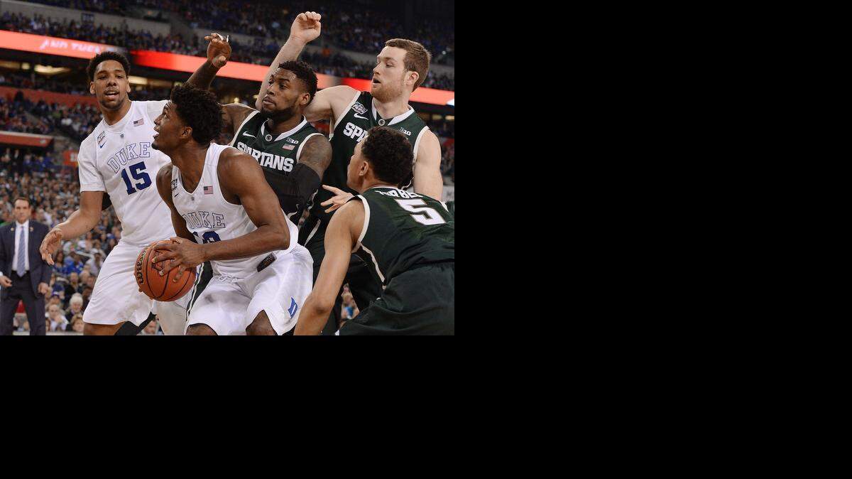 
Duke forward Justise Winslow (12) and teammate center Jahlil Okafor (15) draw a crowd of Michigan State defenders under the basket in the second half of play. Duke will advance to the NCAA national championship game after defeating Michigan State 81-61 at Lucas Oil Stadium in Indianapolis, Indiana Saturday, April 4, 2015.
