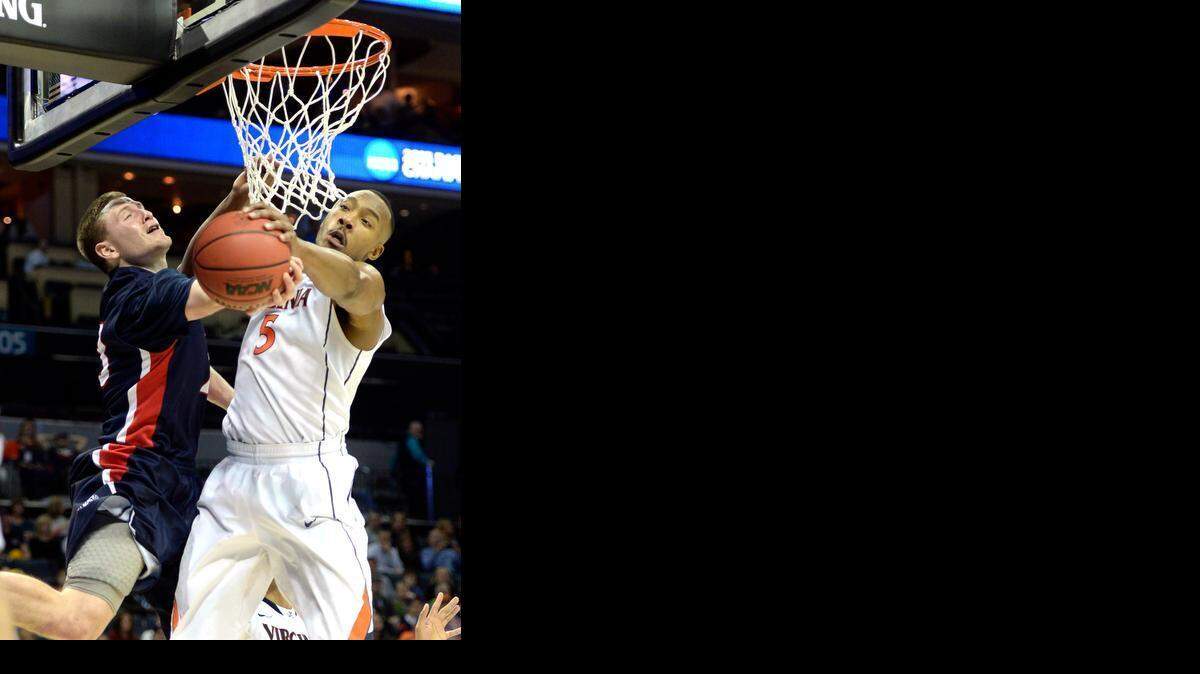 
Belmont Bruins' Craig Bradshaw (23) gets blocked by Virginia Cavaliers' Darion Atkins (5) in the first half of their second round of the NCAA men's basketball tournament at Time Warner Cable Arena on Friday, March 20, 2015. 
