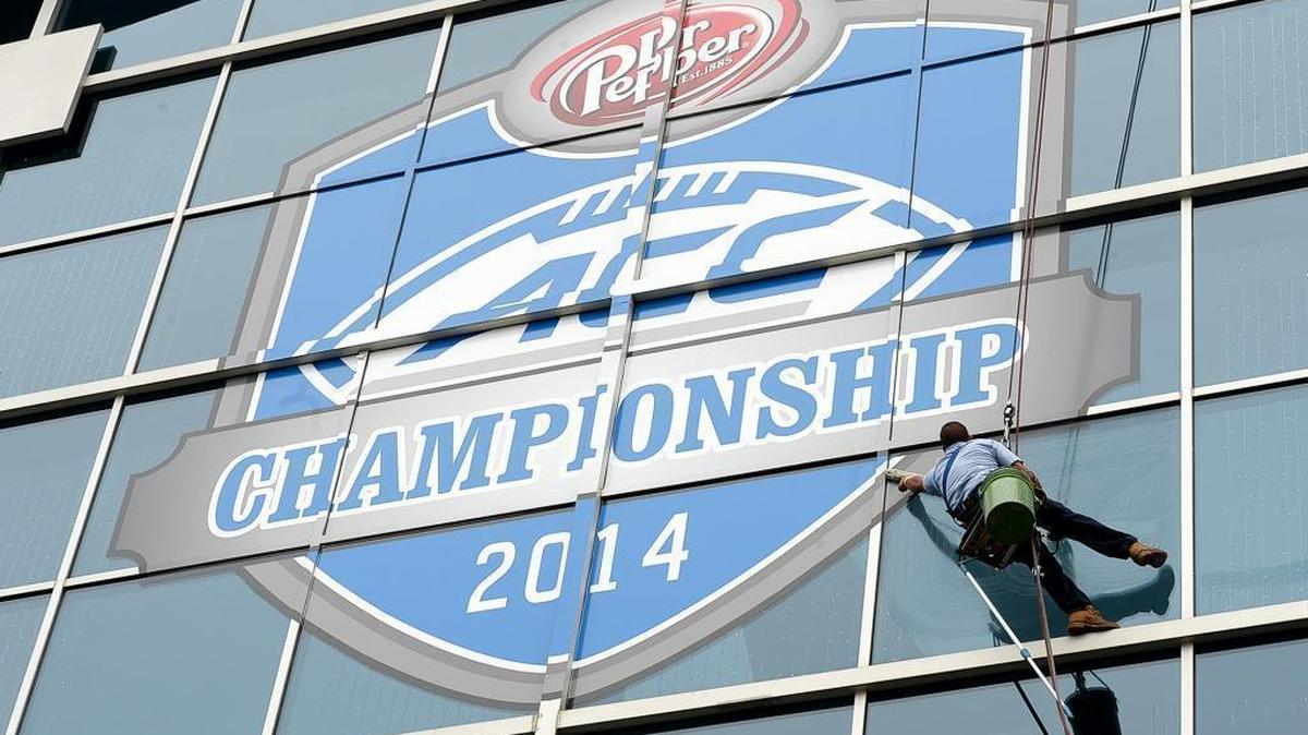 A window washer cleans the ACC Championship logo on the side of Bank of America Stadium in preparation for the 2014 ACC Championship game.