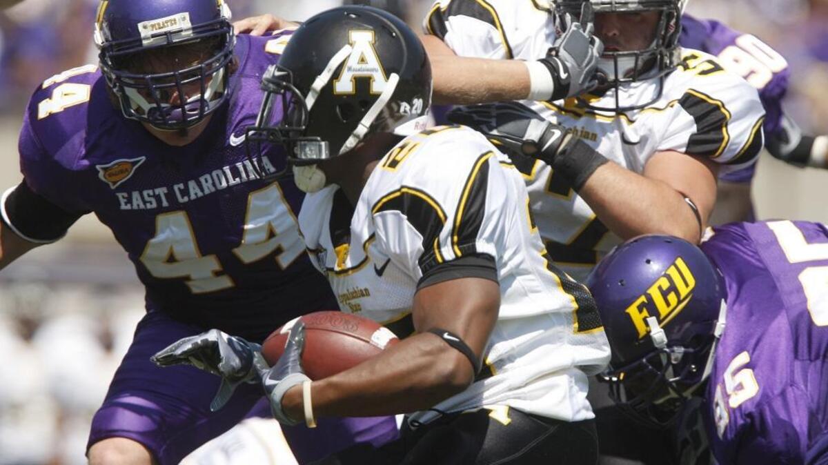 In their football game in September 2009 in Greenville, Appalachian State's Devon Moore (center) finds running room against East Carolina's defense. However, the Pirates held off the Mountaineers 29-24. Wednesday, the schools agreed to a three-game series that will include a game at Bank of America Stadium in Charlotte.