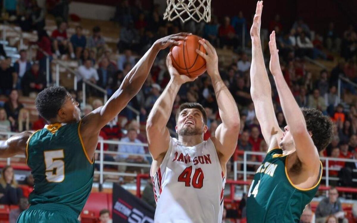 Davidson’s Andrew McAuliffe (40) is stopped at the basket by George Mason's Jaire Moore (05) and Daniel Relvao (14) during Wednesday’s game.