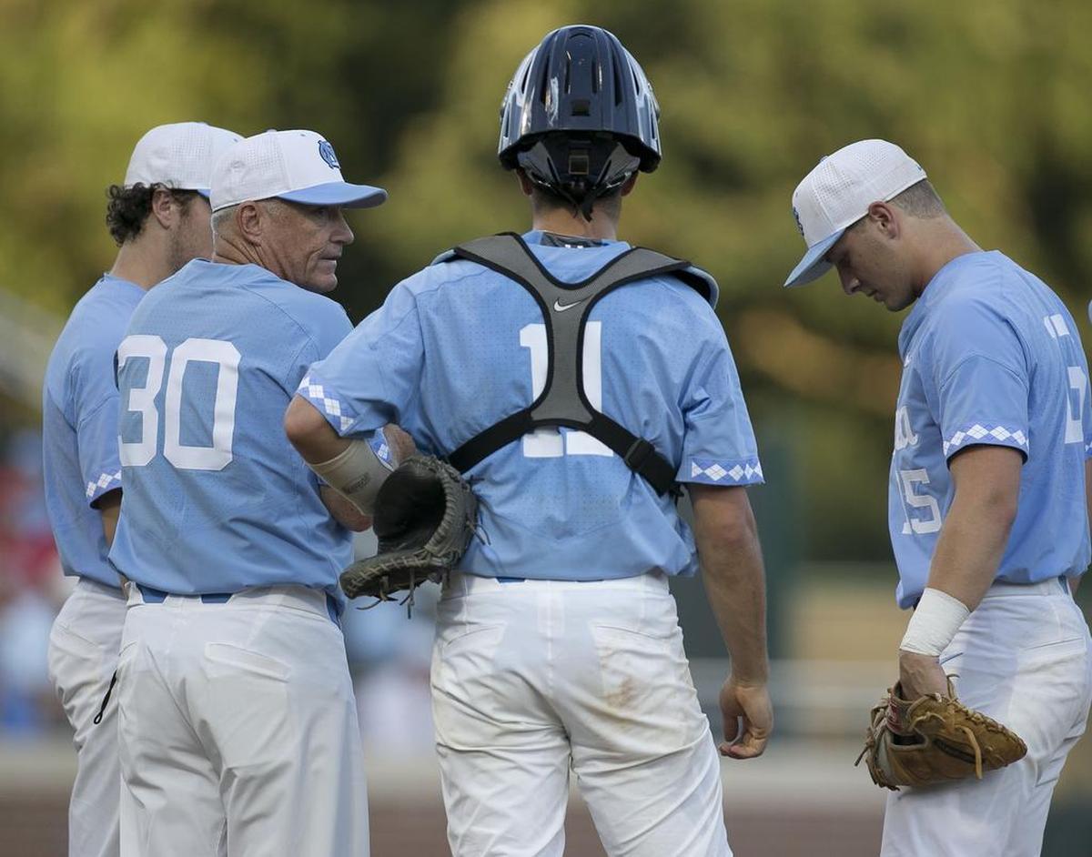North Carolina coach Mike Fox confers with catcher Cody Roberts and Michael Busch, right, after making a pitching change in the fifth inning .