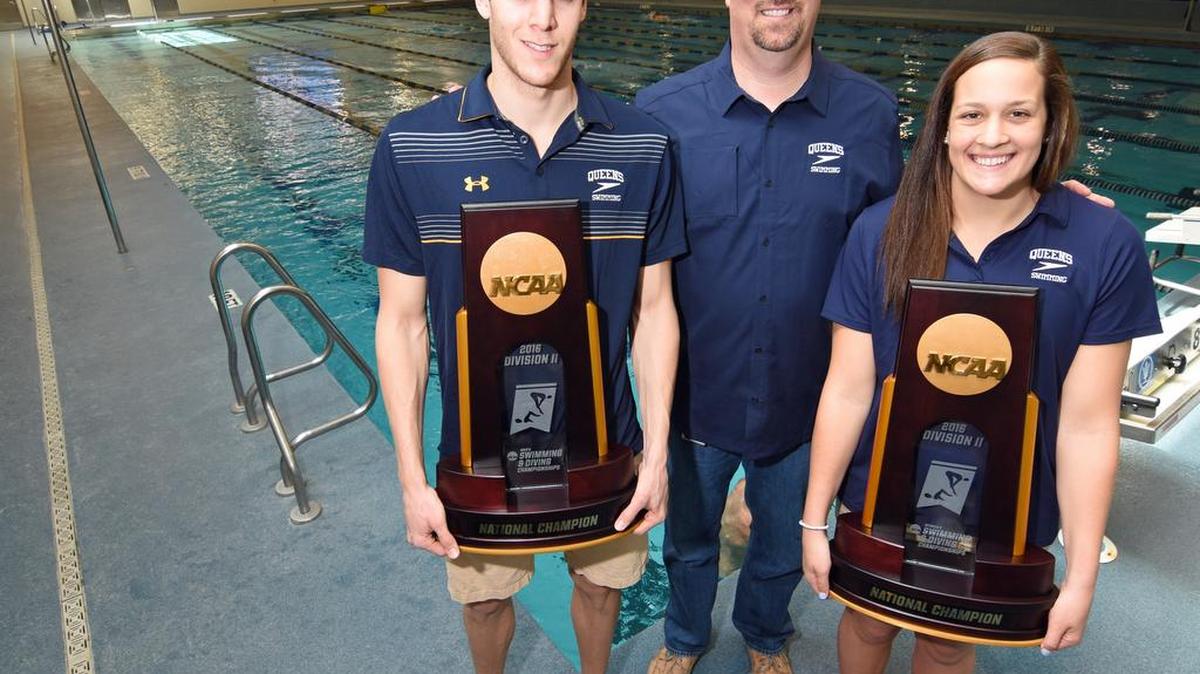 Flanked by Queens swim coach Jeff Dugdale (center), Royals swimmers Dion Dreesens (left) and Caroline Arakelian (right) hold the men’s and women’s championship trophies from the 2016 NCAA Division II National Championships, held March 9-12, 2016, in Indianapolis, Ind. Queens repeated as men’s and women’s champions, and Dreesens was named the men’s most outstanding swimmer. In addition, Queens swimmer Patricia Castro-Ortega (not pictured) was named the women’s most outstanding swimmer for the second straight year. CREDIT: Bill Kiser/Special to the Observer