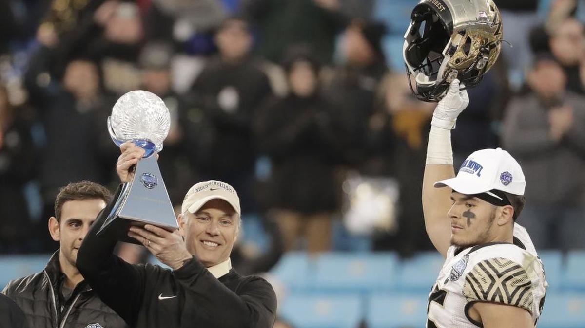 Wake Forest coach Dave Clawson, left, raises the trophy as tight end Cam Serigne celebrates after the Deacons beat Texas A&M 55-52 in the Belk Bowl Friday afternoon at Bank of America Stadium in Charlotte.