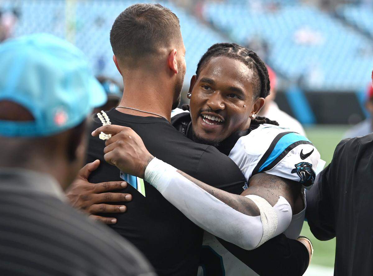 Carolina Panthers head coach Dave Canales, left hugs running back Rico Dowdle, right, following the team's 27-24 victory over the Miami Dolphins on Sunday, October 5, 2025 at Bank of America Stadium in Charlotte, NC.