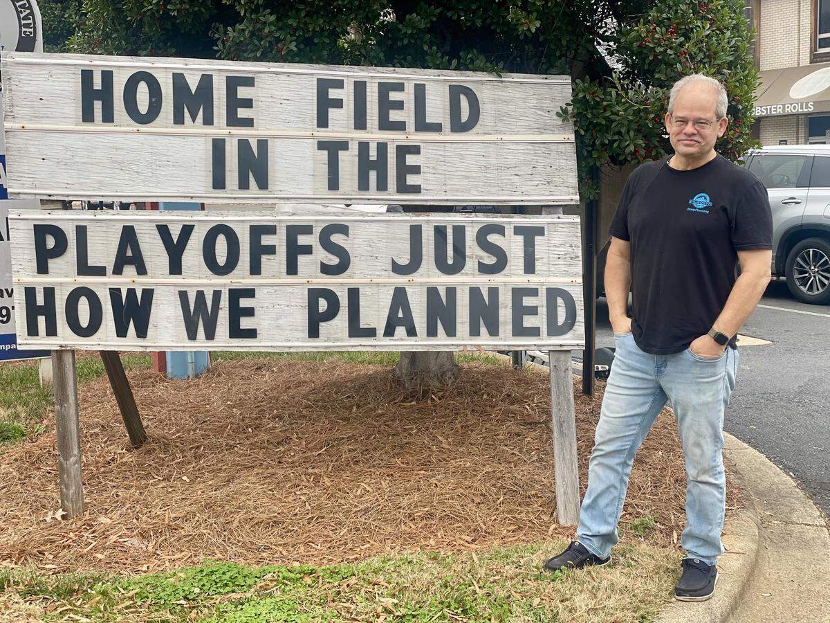 The owner of Dilworth Neighborhood Grille, Matt Wohlfarth, stands next to the sign that he changes each week and has gradually watched become a voice for Carolina Panthers fans and the Charlotte community.