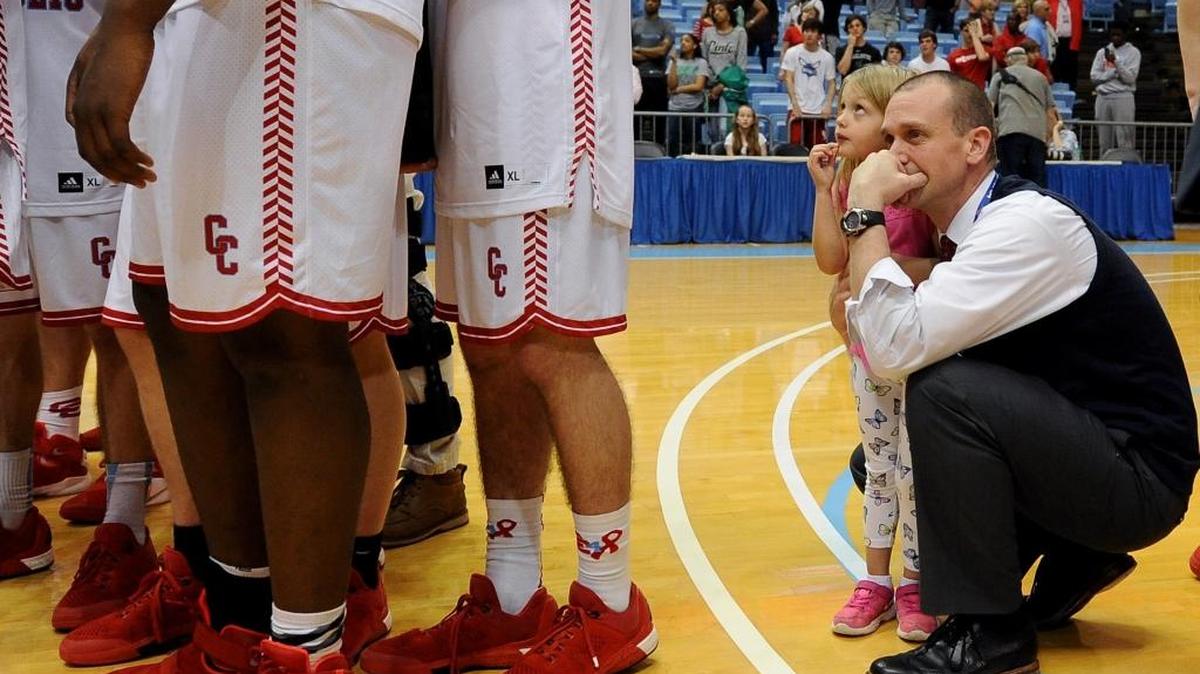 Charlotte Catholic Cougars head coach Mike King, right, crouches with his daughter watching as his team receives their medals following their victory over Cary in the NCHSAA 4A state finals at the Dean E. Smith Center in Chapel Hill, NC on Saturday, March 12, 2016. Catholic defeated Cary 49-46. King is the SoMeck 8 boys basketball coach of the year