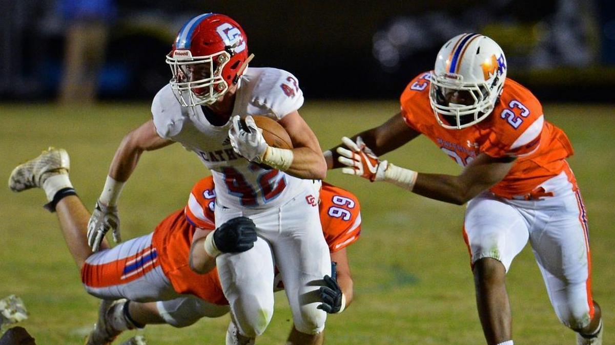 Charlotte Catholic running back/wide receiver Michael Neel is able to pick up yardage as Marvin Ridge's defensive tackle Brae Lein, left and defensive lineman Jonathan Clark, right, attempt to make the tackle during second quarter action at Marvin Ridge High School on Friday, November 3, 2017.