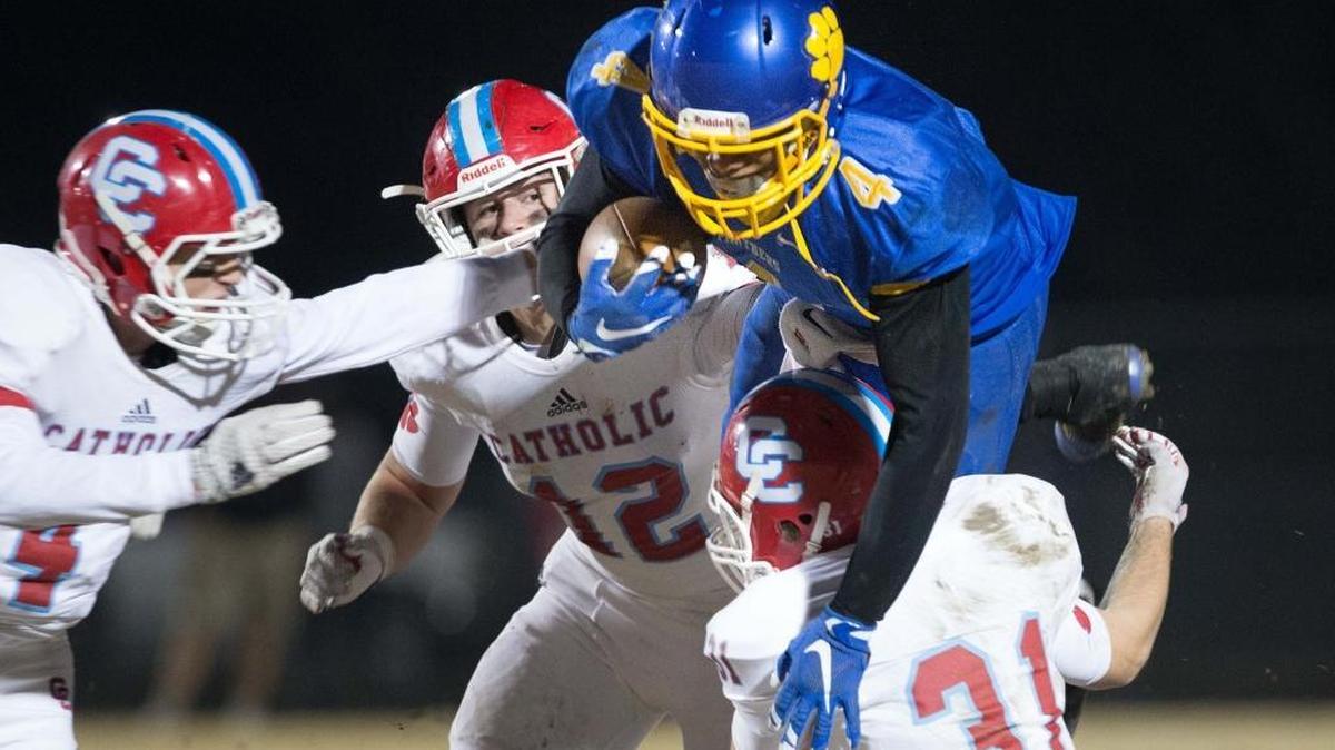 Dudley's Simeon Gatling (4) goes over Charlotte Catholic’s Andrew Brouse (31) on the carry with Charlotte's Benjamin Brodowicz (4) and Alexander Gagnon (12) trying for the stop as Dudley plays Charlotte Catholic for the 4-A West Regional football championship on Friday in Greensboro.