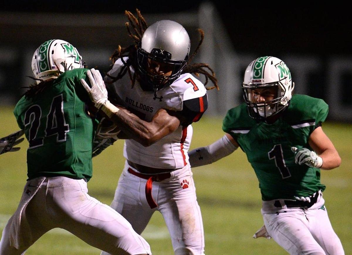Butler Bulldogs running back Quasean Holmes, center, battles his way between Myers Park defenders defensive back Kenyatta Howie, left and defensive back Patrick Alvarez, right, during fourth-quarter action on Friday, Oct. 6, 2017 at Myers Park High School. Butler defeated Myers Park 28-7.