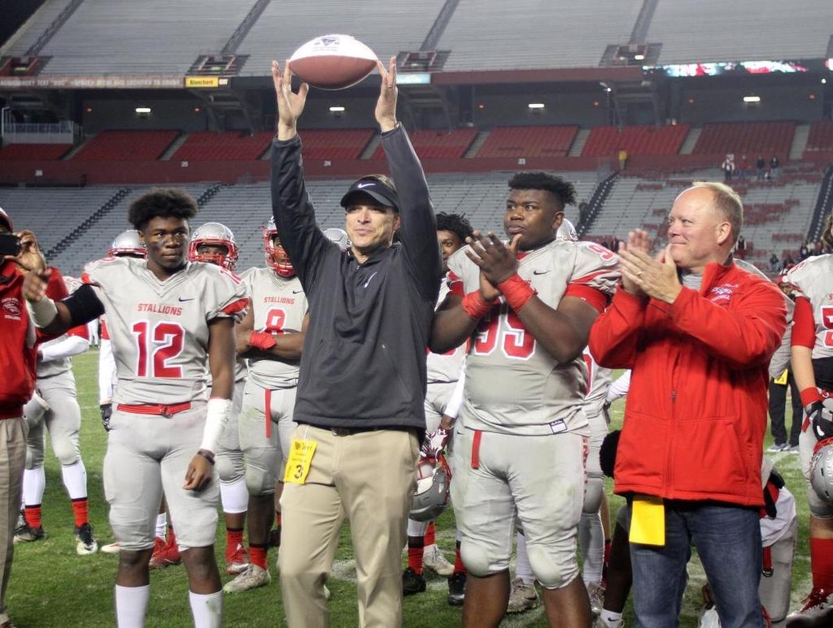 South Pointe High School varsity football coach Strait Herron holds up a football after the team wins the state championship game.