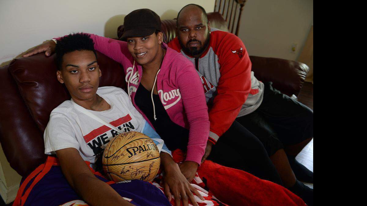 
Tariq and his parents, Fatimah Myrick andAlonzo Massenburg, pose in their living-room. Tariq Massenburg's heart was simply too big. It caused him to pass out during practice last Sunday at United Faith Christian after having a scary seizure where he fell from the stage onto the floor. CPR was performed on Massenburg, who went cold and limp and had no pulse. Parademedics lost him twice as his teammates stood around to pray for his life, crying. Finally, Tariq came back. "It was," coach Kevin Ligon said, "a true miracle.”
