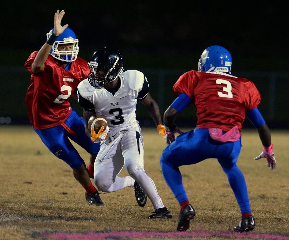 In 2015, Hough wide receiver Marquill Osborne, center, broke between North Meck defensive lineman Tre Turner, left, and defensive back De'Montrez Burroughs, right, in Hough’s 30-6 win
