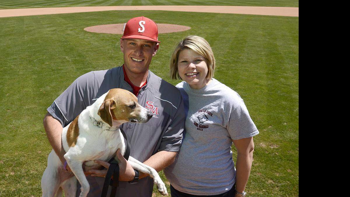 
Jon Tuscan, holding his dog, Mick, and his wife Sarah Tuscan are expecting their first child in late May. The couple and their pet posed for a portrait on Friday, April 24, 2015 at South Meck's baseball field. Two years after winning the state championship, South Meck baseball coach Jon Tuscan is two years clear of having his testicular cancer go into remission, a period where doctors say he is out of the woods. His baseball team is again in the hunt for states, playing rival Providence Tuesday. He was diagnosed after his dog, Mick, jumped his lap with such ferocity that he went to the doctor for pain. That canine leap saved his life. 
