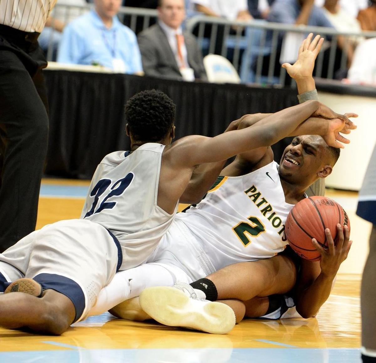 Independence’s Jamarius Burton, right, tangles on the floor with a loose ball against Wake Forest Heritage’s Jarren McAllister during Saturday evening's NCHSAA 4A state basketball championship game at the Smith Center in Chapel Hill.